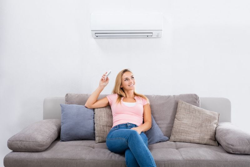 Image of person sitting below ductless system. Ductless ACs Improve Indoor Air Quality and Control Humidity.