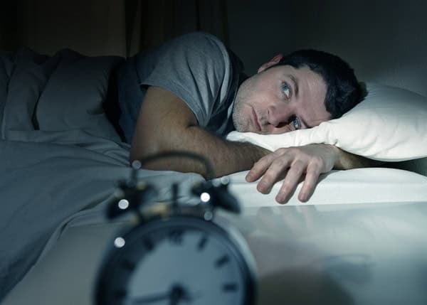 Man trying to sleep after realizing the loud sound coming from his furnace system.