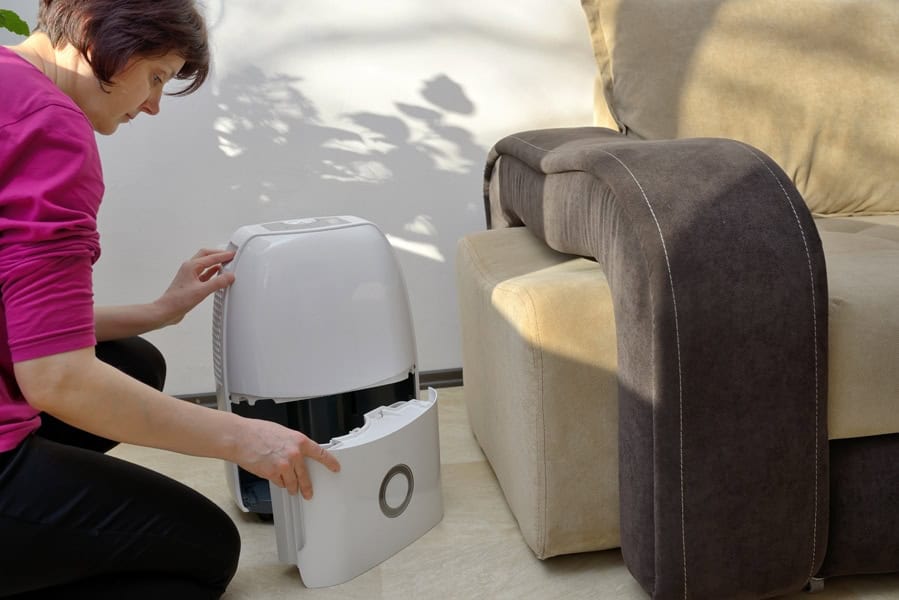 A woman checking her humidifier to show why your need whole-house humidifiers to help control the level of humidity in your home.