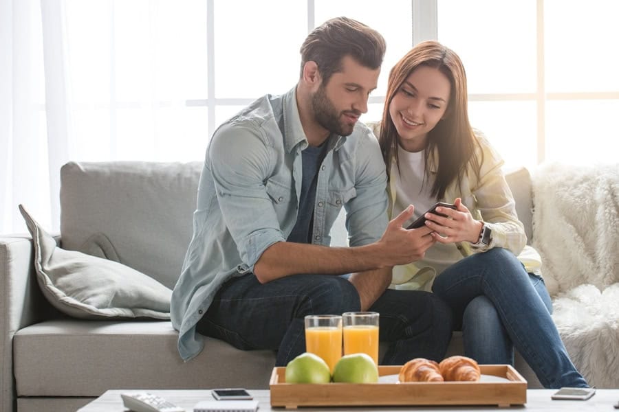 Man and woman reading article on phone learning what indoor air quality accessories can help keep them healthy.