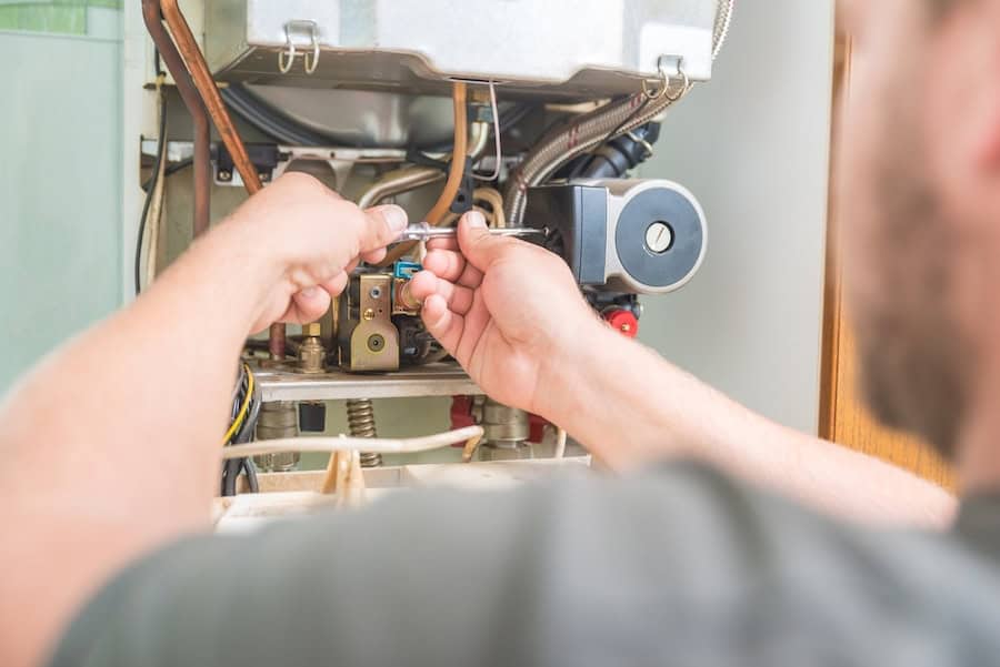 Blog Title: How Do I Know I Have a Cracked Heat Exchanger? Photo: Tech repairing gas furnace close up