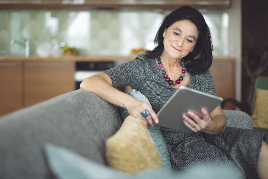 Woman reading maintenance tips for how to care for her home's heat pump unit.