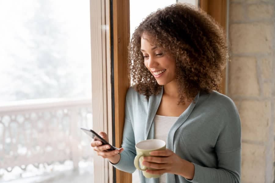 Woman researching the different types of furnaces by window in her home.